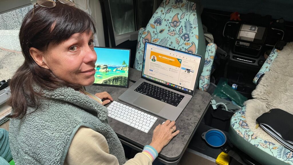 Coach arbeitet im Camper an Laptop und Bildschirm an LinkedIn Content und Kundengewinnung.